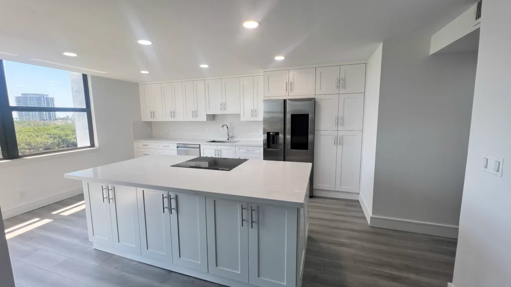 Kitchen island with sink and shaker drawers, lit by a corner window