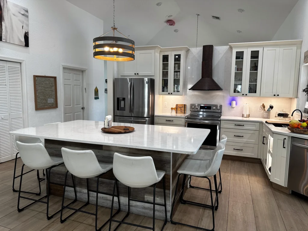 White shaker kitchen with a quartz island seating four and a black range hood