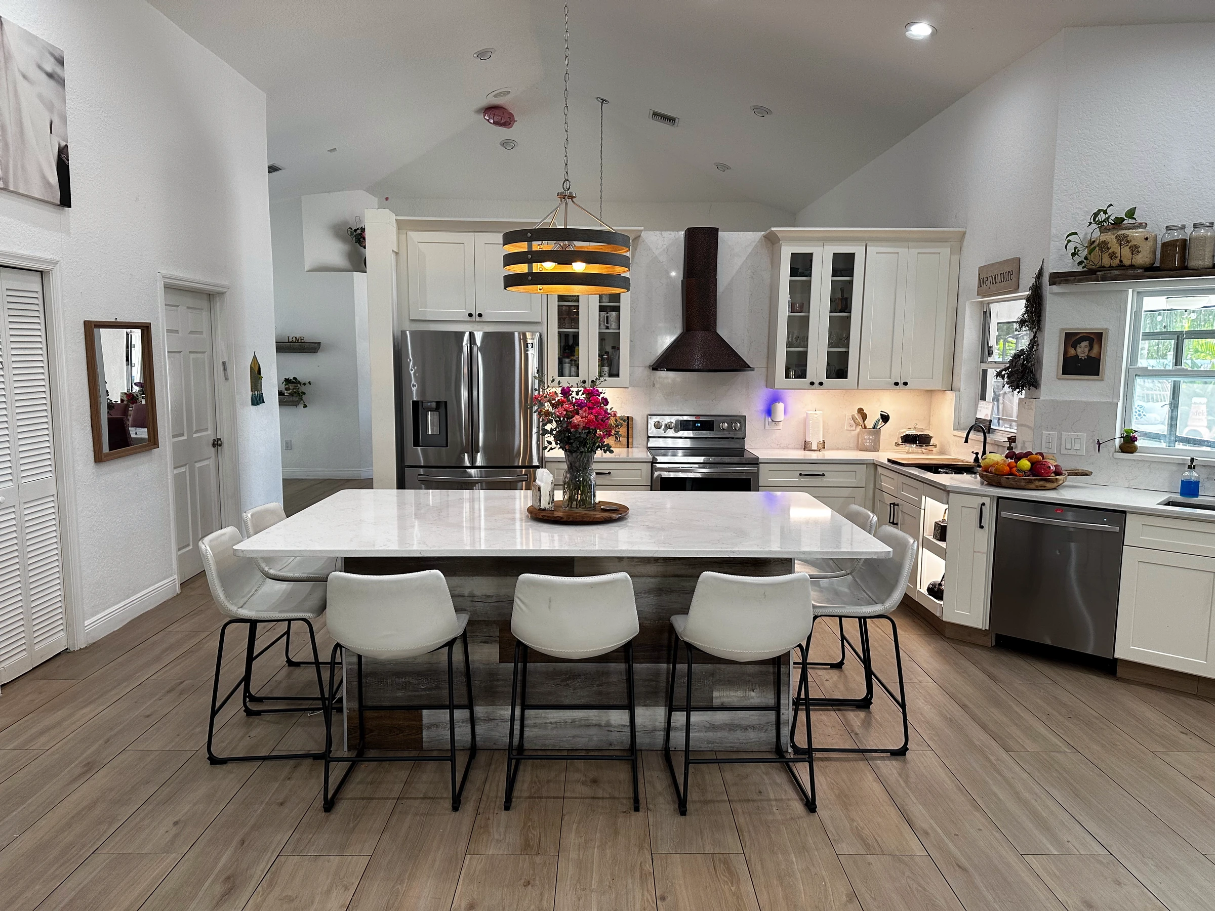 Wide view of an open kitchen with white cabinets, a large island and wood-look floors