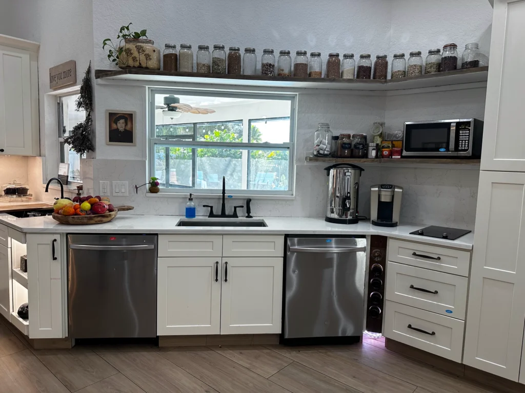 Sink wall with white cabinets, stainless dishwashers and open shelving
