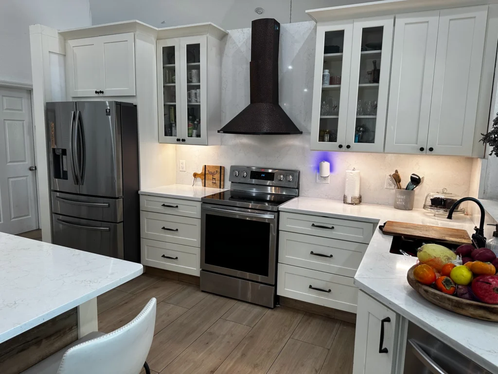Range wall with a black chimney hood, glass-front upper cabinets and stainless appliances