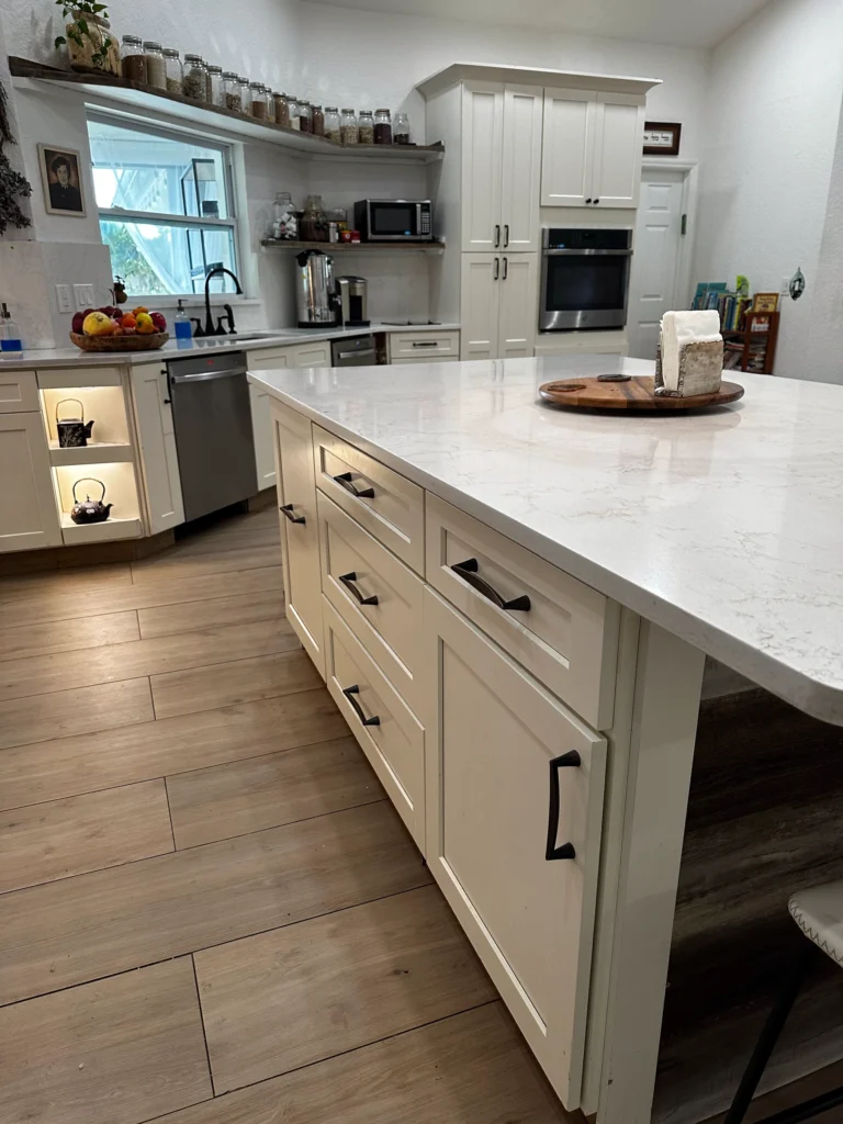 Side view of a white kitchen island with drawer storage and a quartz top
