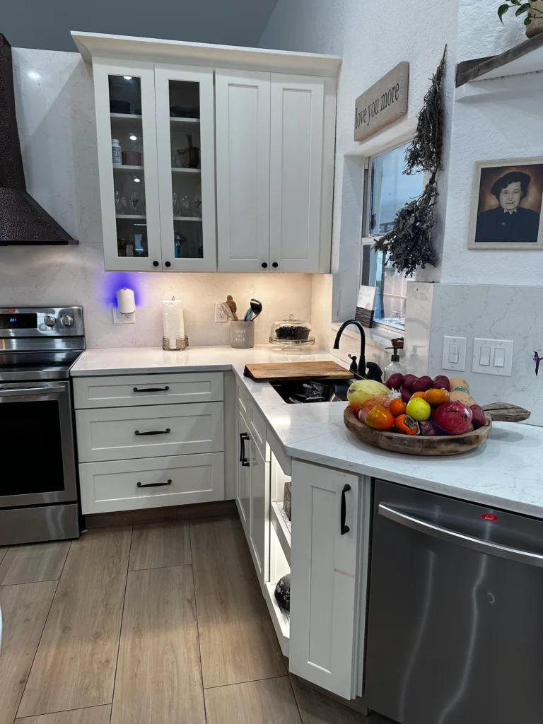 Corner of a white kitchen with glass-front cabinets and under-cabinet lighting