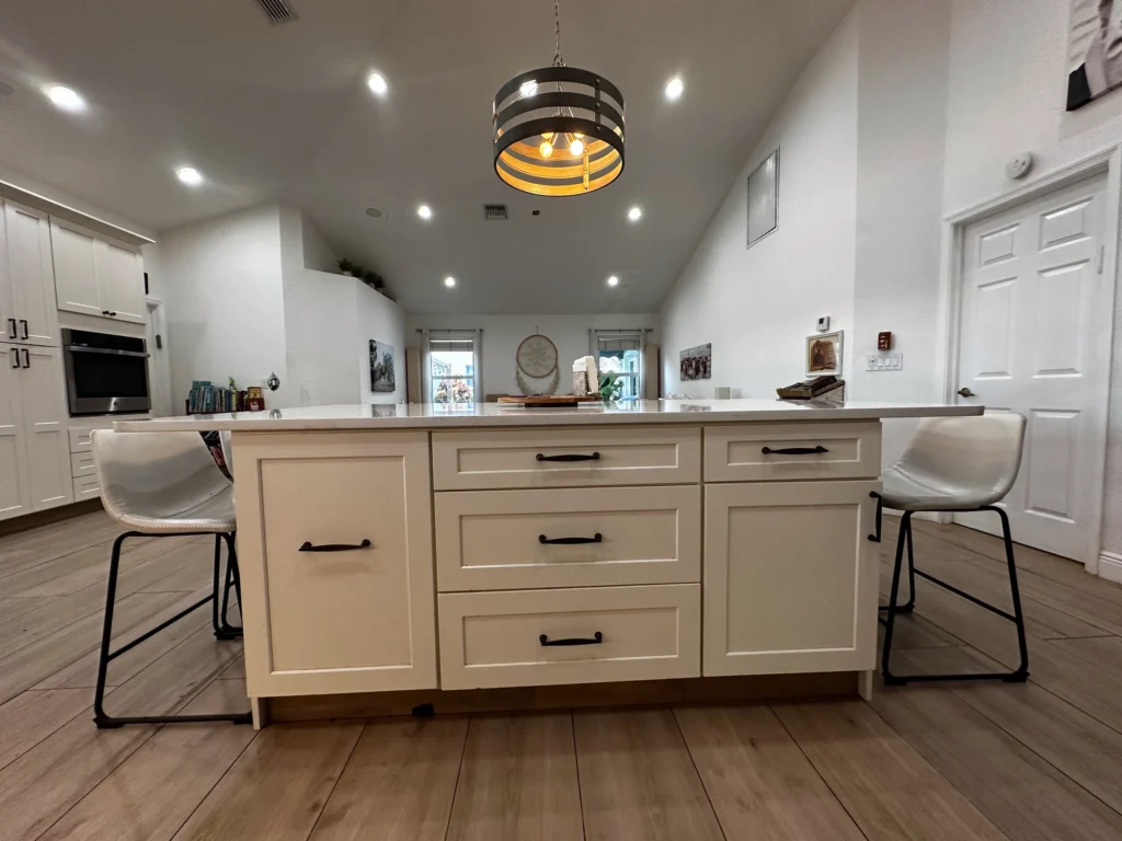 Front of a white island with drawers and bar stools