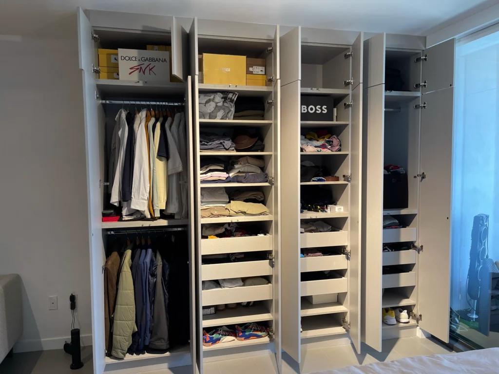 The built-in closet open, showing hanging space, shelves and pull-out drawers