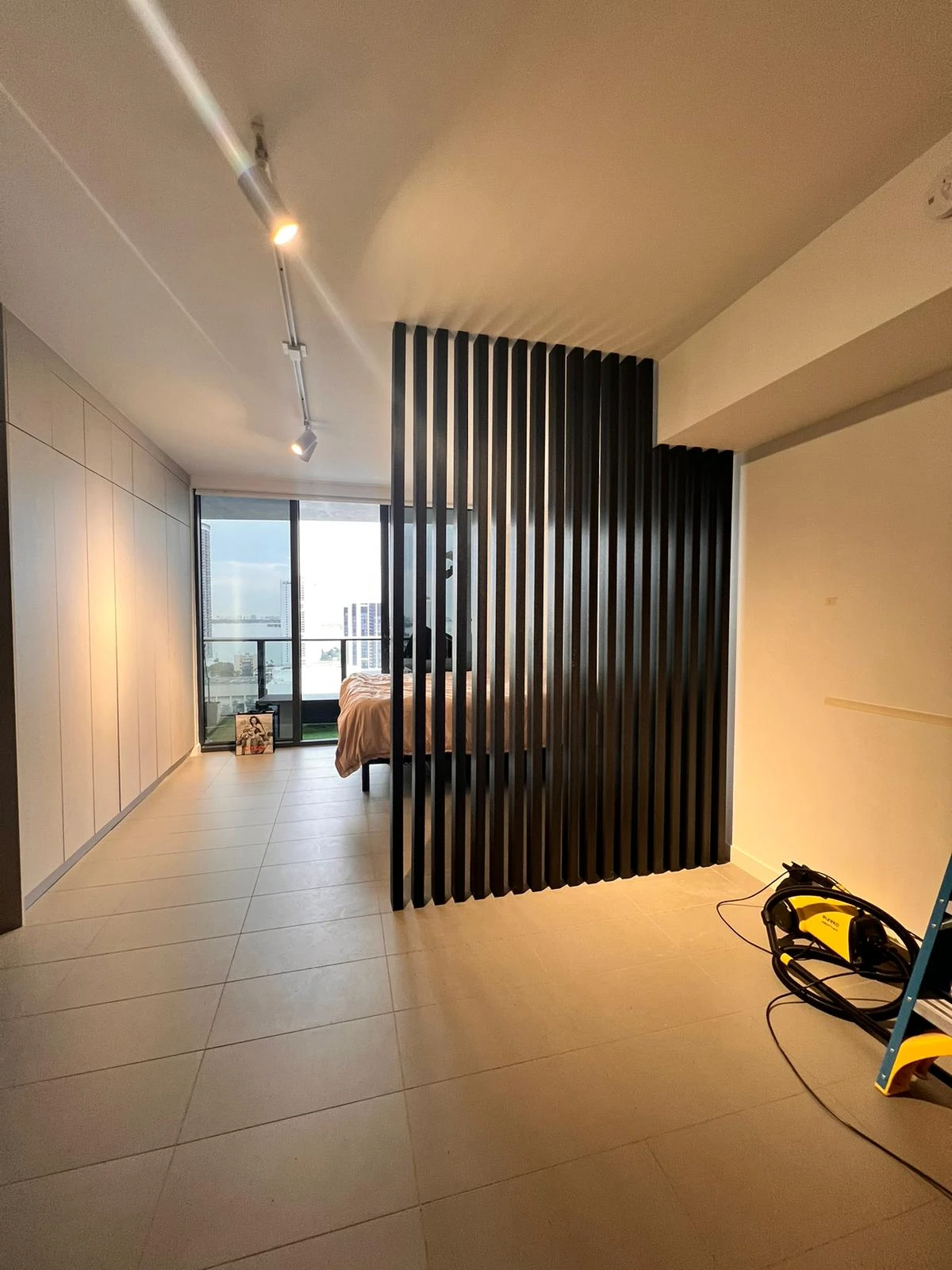 Dark wood slat divider separating the sleeping area in a studio apartment