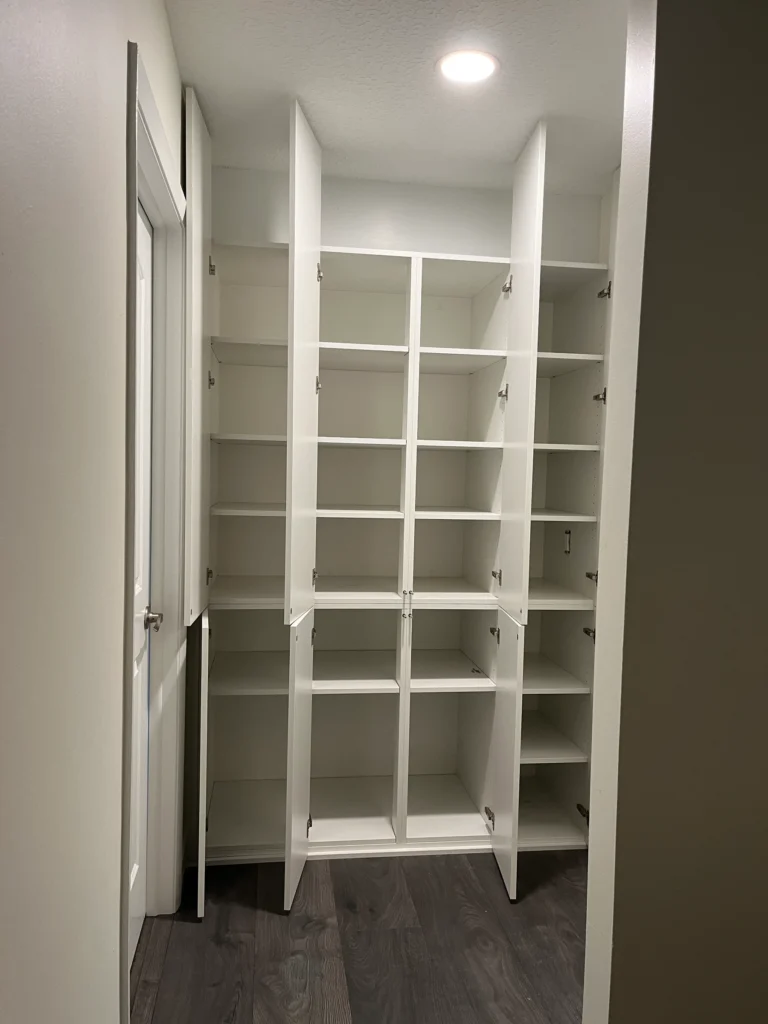 The built-in closet with its doors open, showing adjustable shelves from floor to ceiling