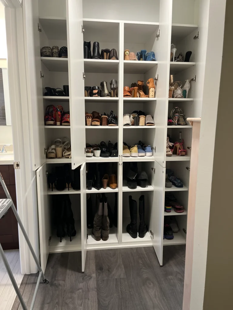 The closet in use as a shoe wall, with shoes on every shelf and boots below