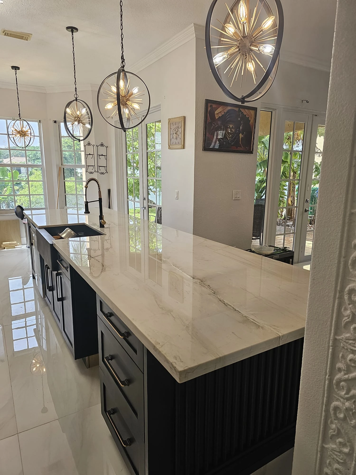 Long kitchen island with sputnik pendants and a view to the windows
