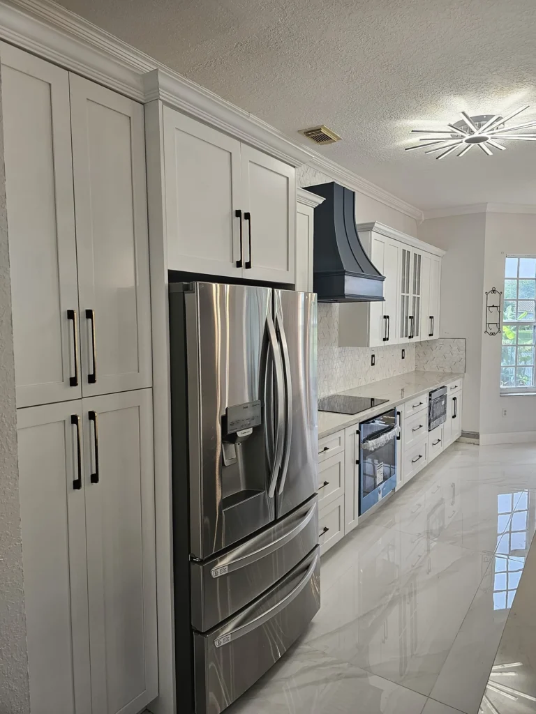 White shaker cabinets with a custom navy range hood and French-door refrigerator
