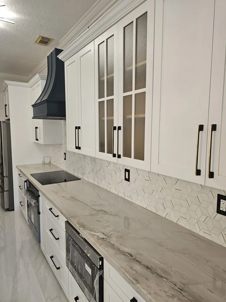 Glass-front upper cabinets over a marble-look counter and herringbone backsplash