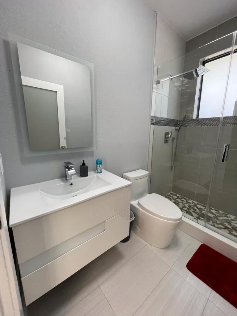 Guest bathroom with a floating white vanity, frameless glass shower and mosaic floor