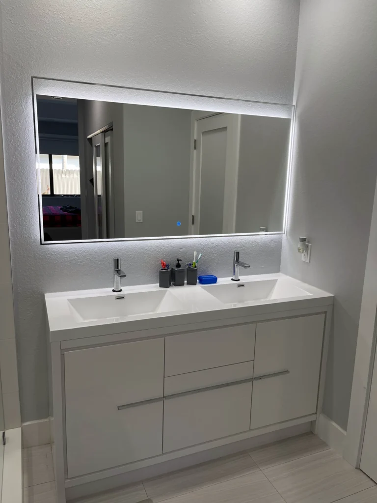 Double vanity in light gray with two sinks and a backlit mirror