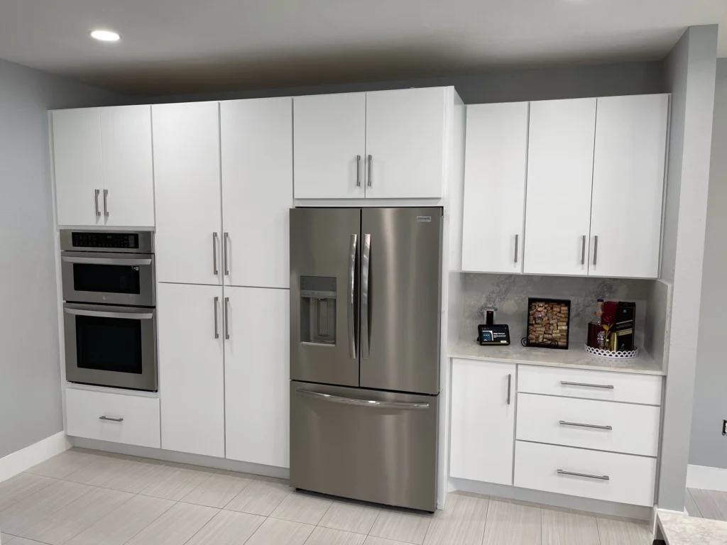 Wall of white flat-panel cabinets with double wall ovens and a French-door refrigerator