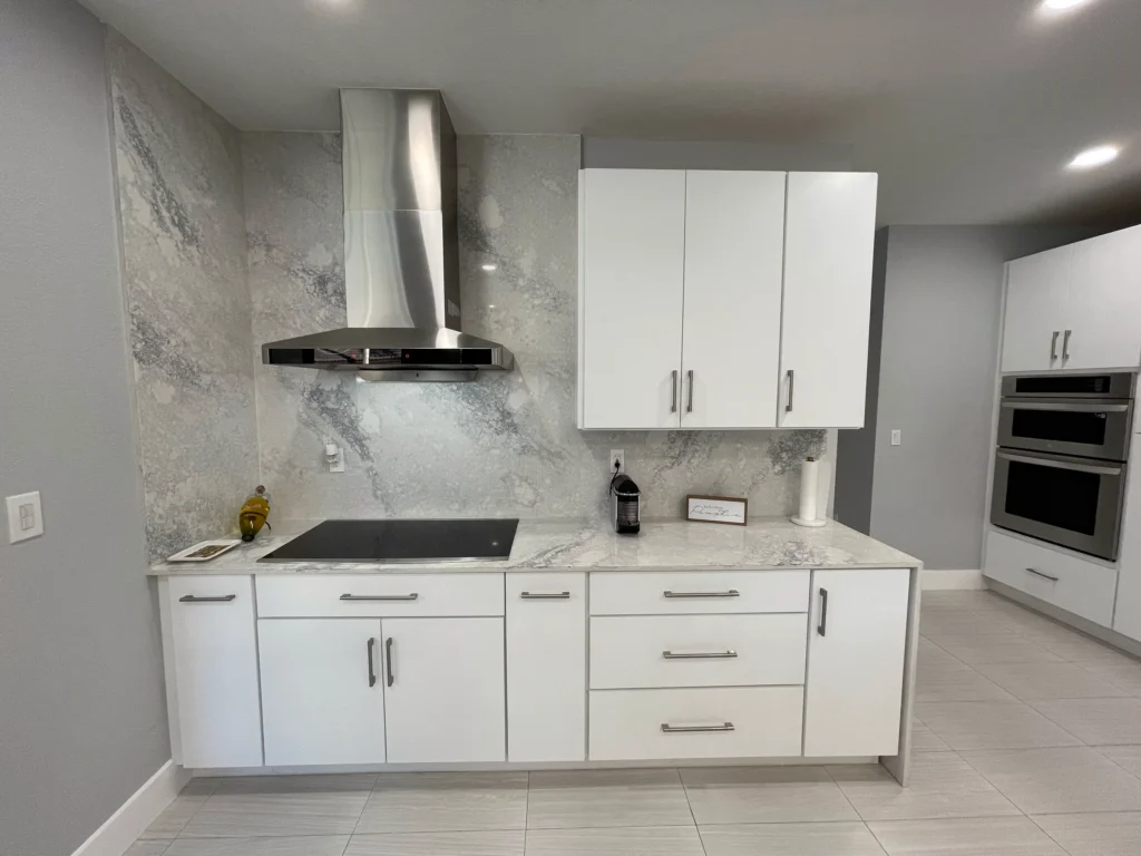 Cooktop wall with a stainless chimney hood and full-height stone backsplash