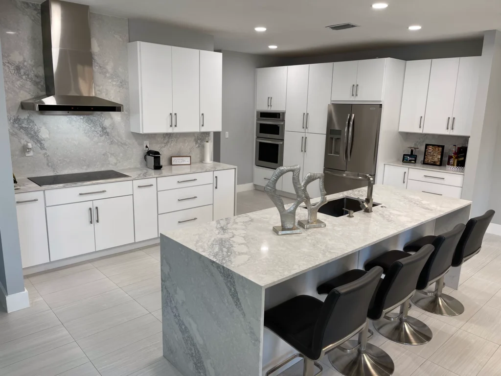Angled view of a waterfall island and white kitchen cabinets