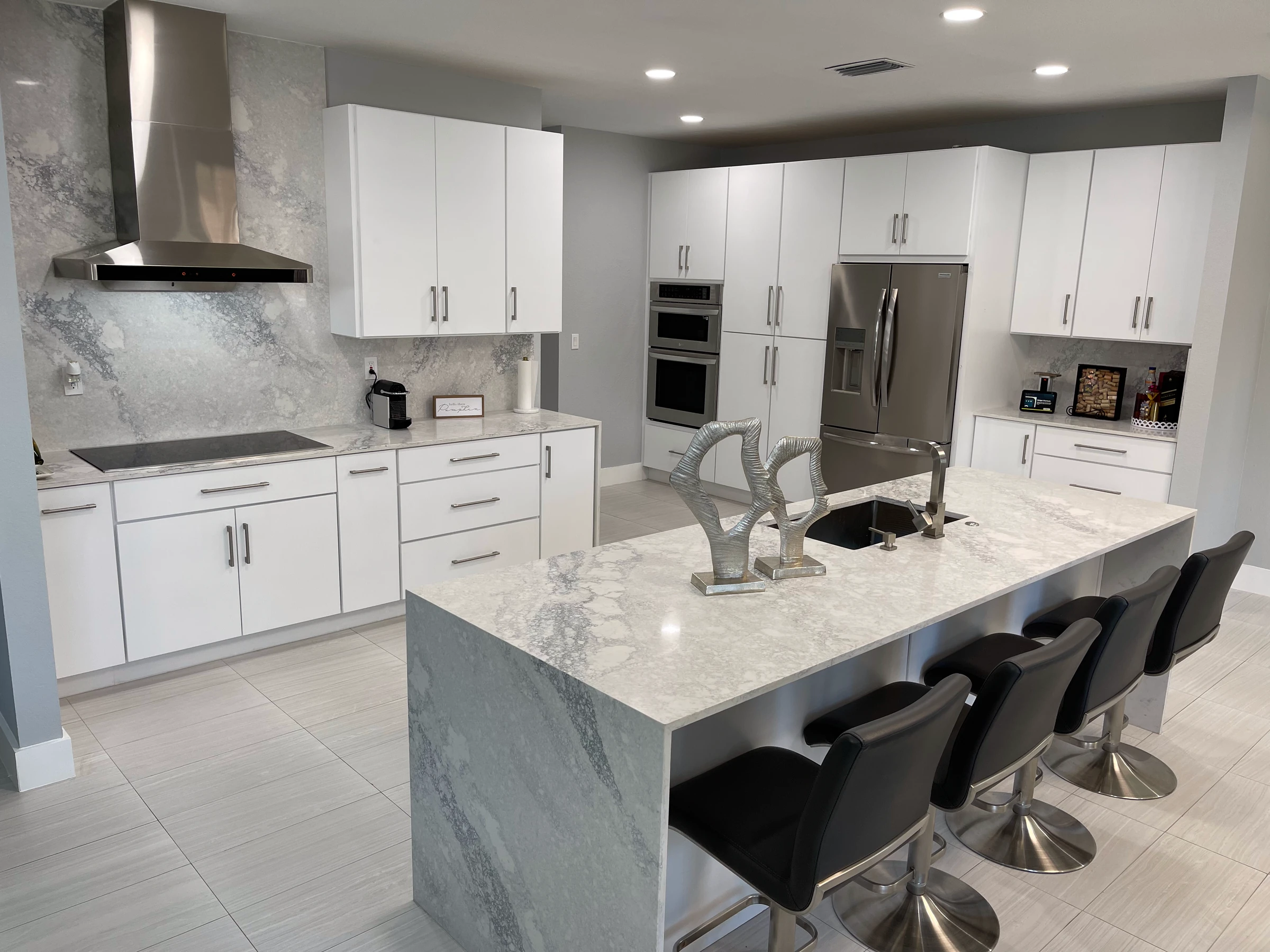 Angled view of a waterfall island and white kitchen cabinets