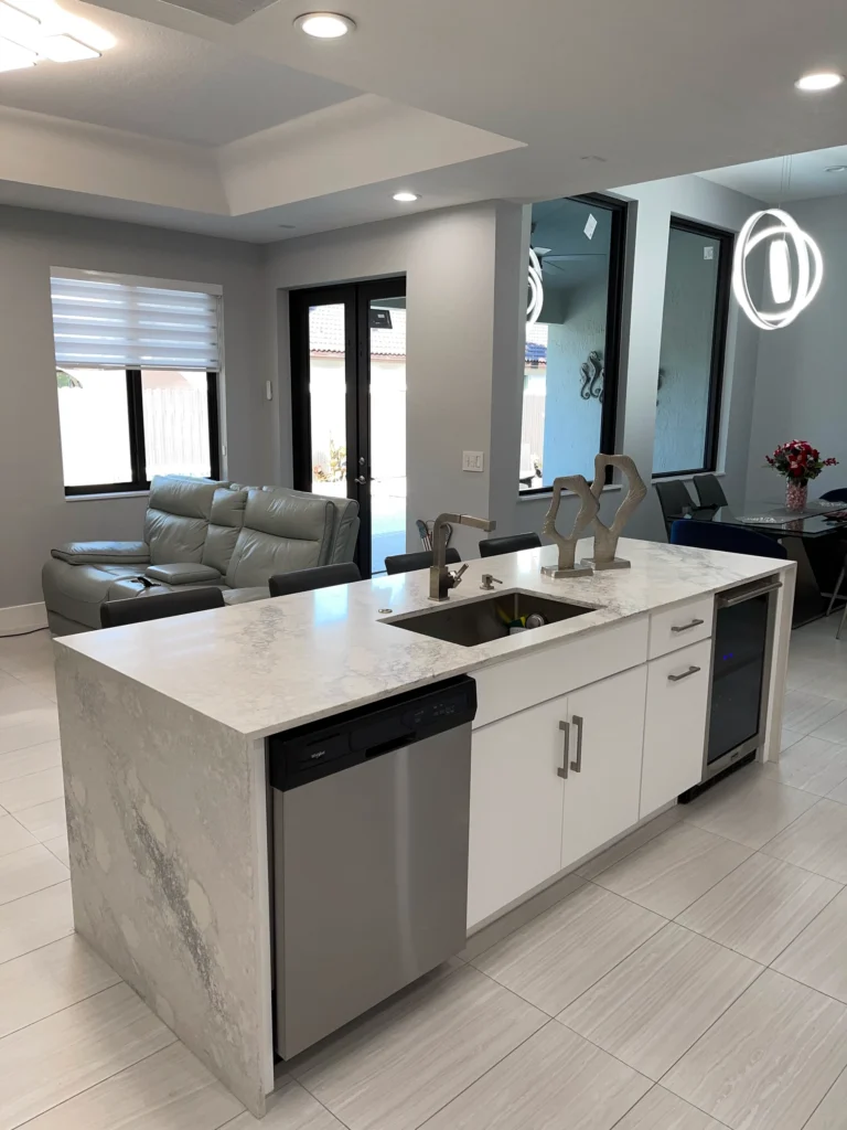 Kitchen island with waterfall edge and undermount sink, family room behind