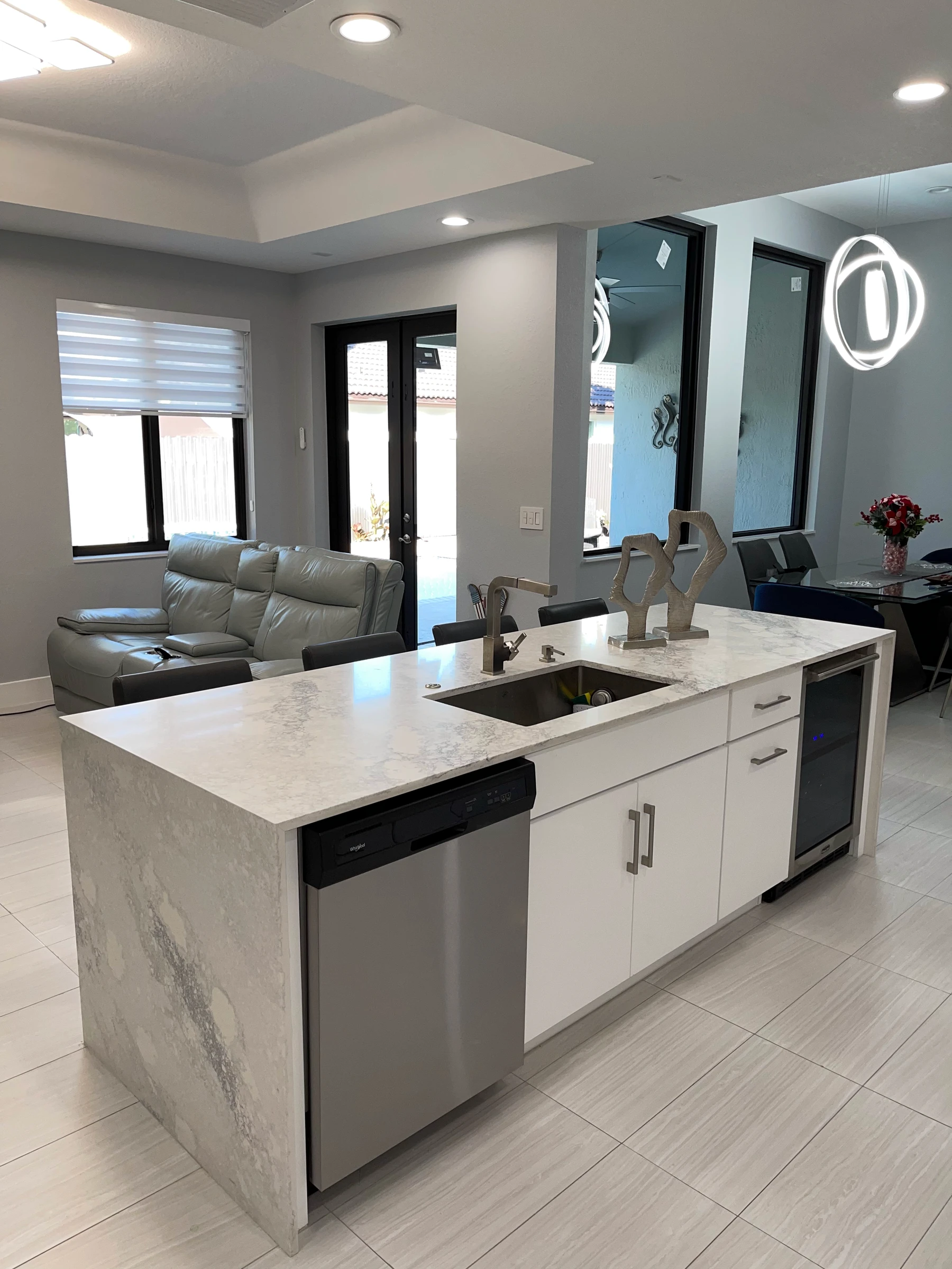 Kitchen island with waterfall edge and undermount sink, family room behind