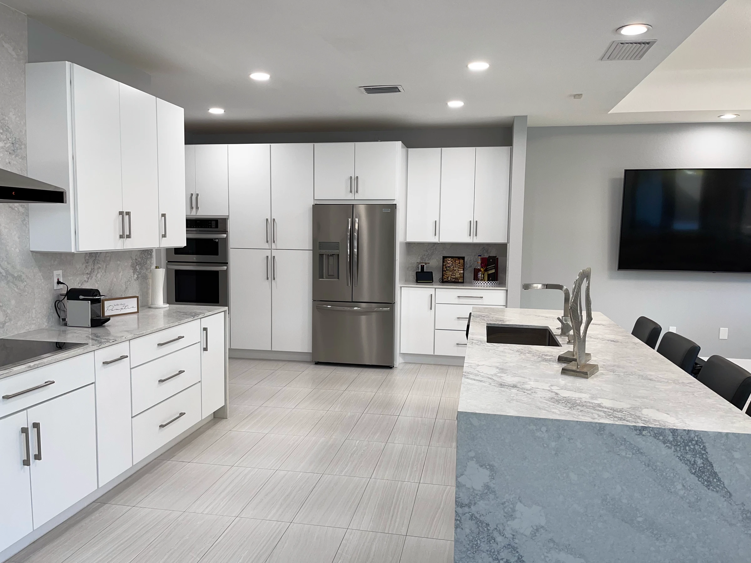 White kitchen with tall cabinets, island and view to the family room