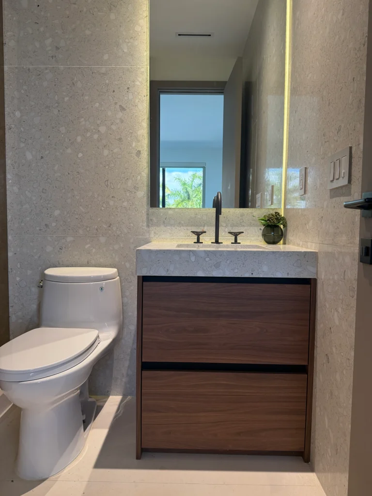 Terrazzo bathroom with a walnut vanity, integrated stone sink and backlit mirror