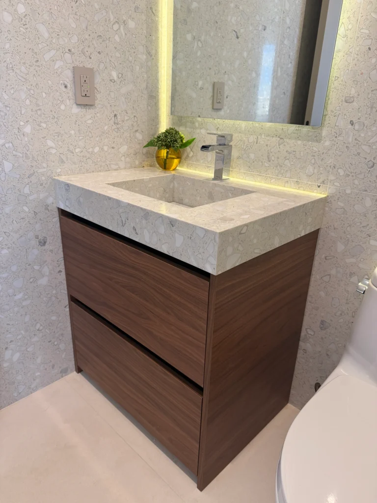 Close view of a walnut vanity with a stone integrated sink and chrome faucet