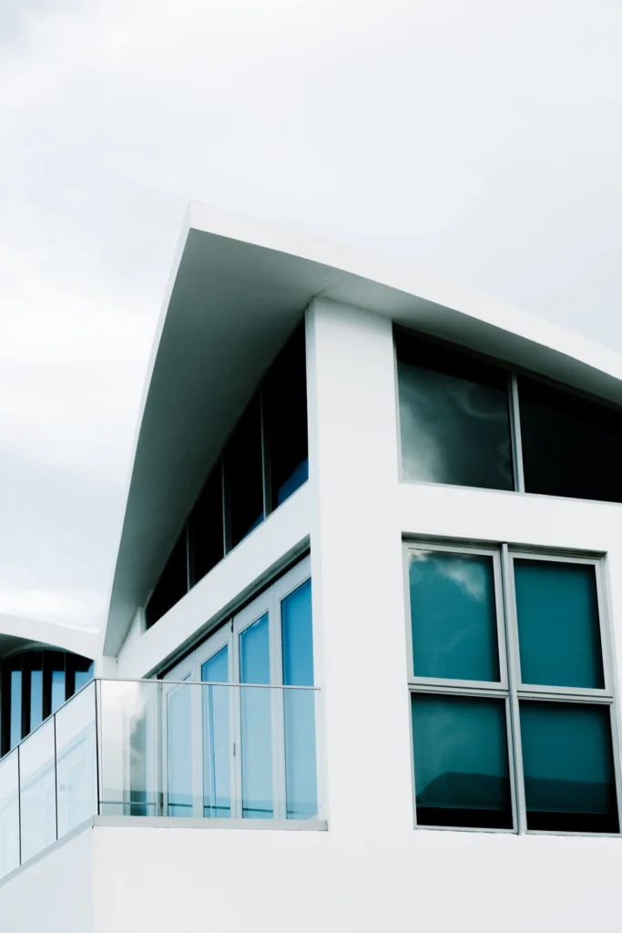Modern white house with large glass windows and a glass balcony railing