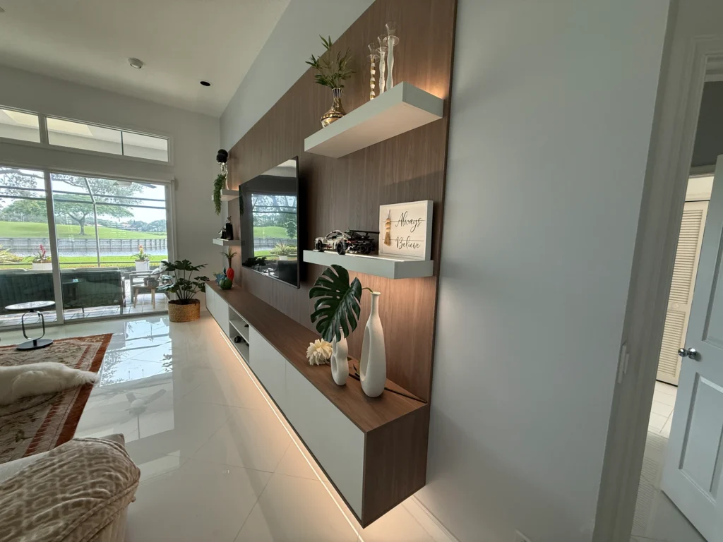 Side view of the TV wall with the floating console lit from below, looking toward the windows