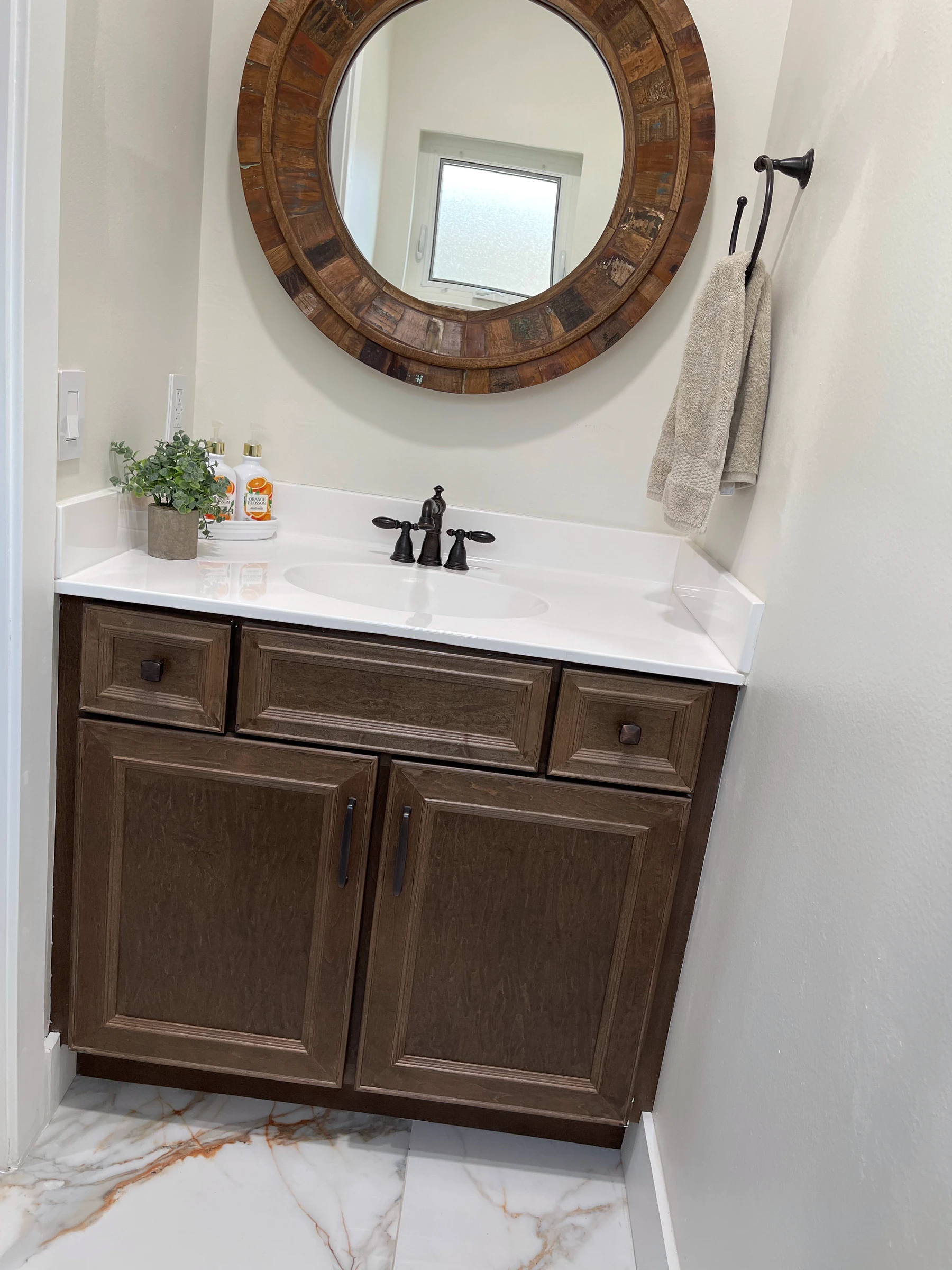 Dark wood vanity with bronze faucet and marble-look floor