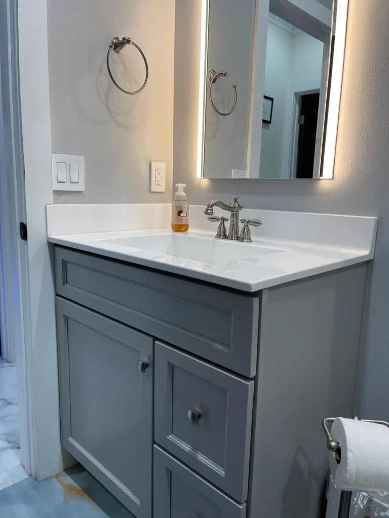 Guest bathroom with a gray shaker vanity and LED mirror