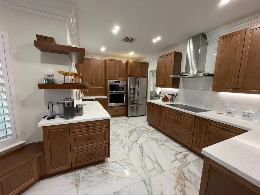 Wood-tone kitchen with white quartz counters, floating shelves and marble-look floor