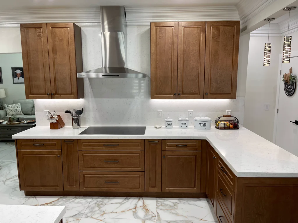 Cooktop wall with stainless hood and raised-panel wood cabinets after the remodel