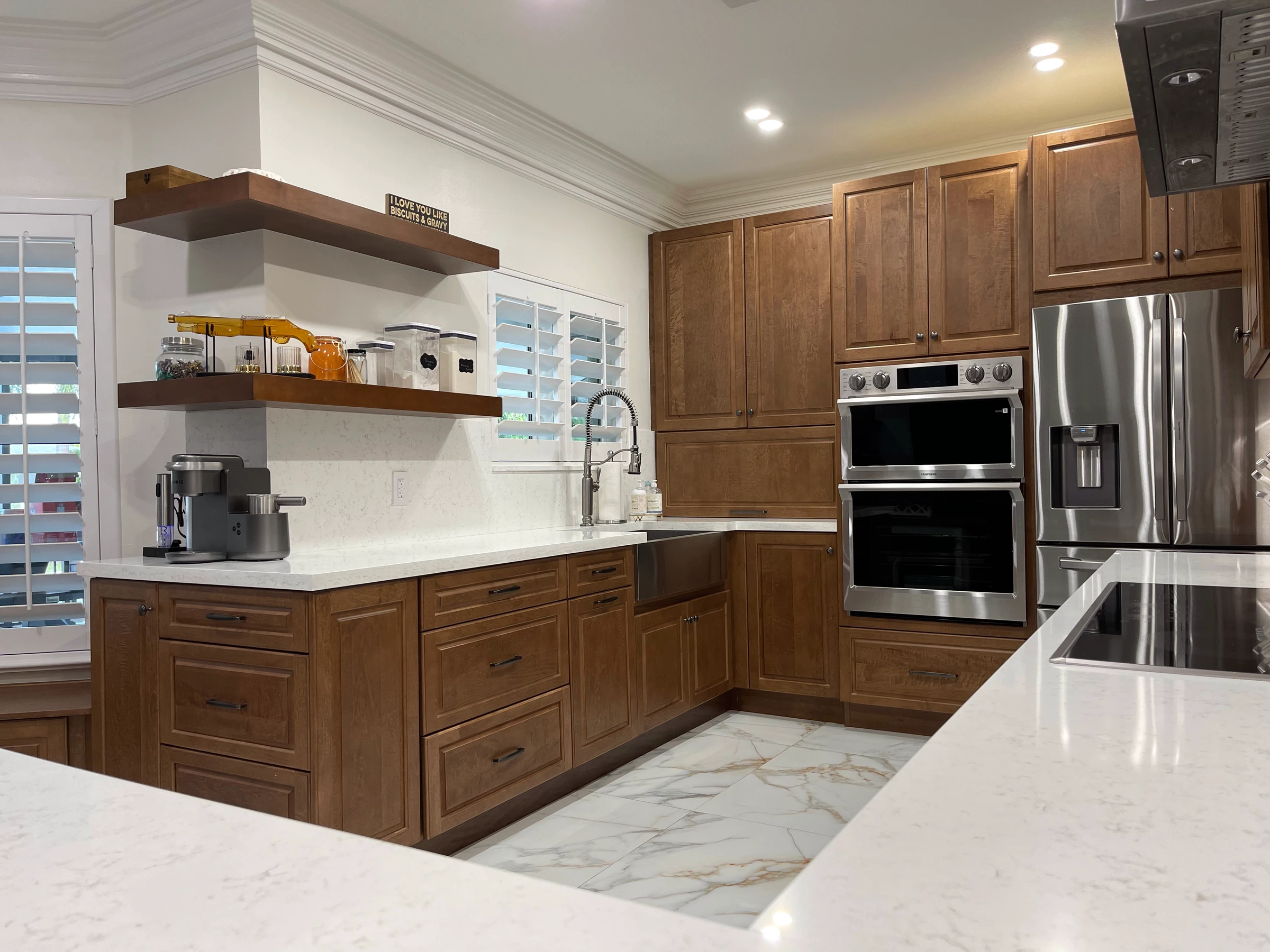 Wall ovens and refrigerator set into wood cabinets, with floating shelves