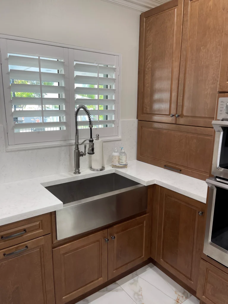 Stainless farmhouse sink with pull-down faucet in a corner of wood cabinets