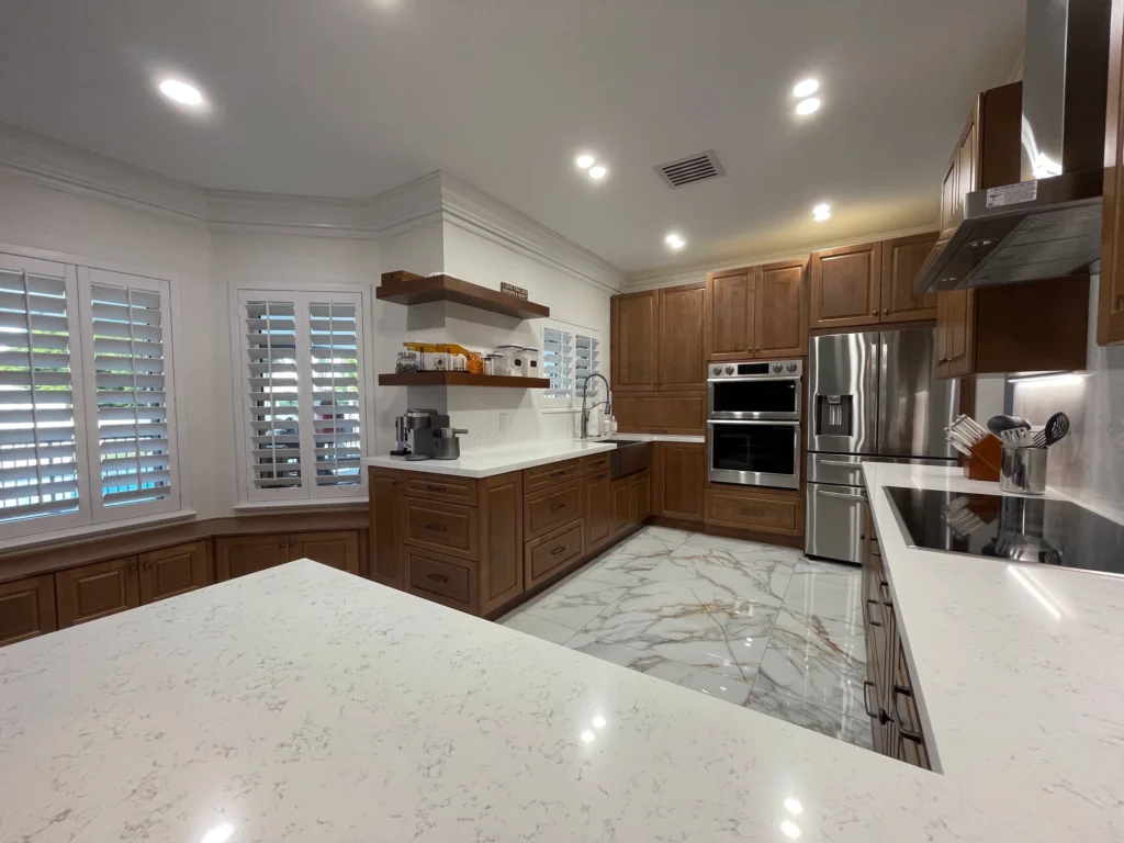 Wood kitchen with floating shelves, wall ovens and a quartz peninsula