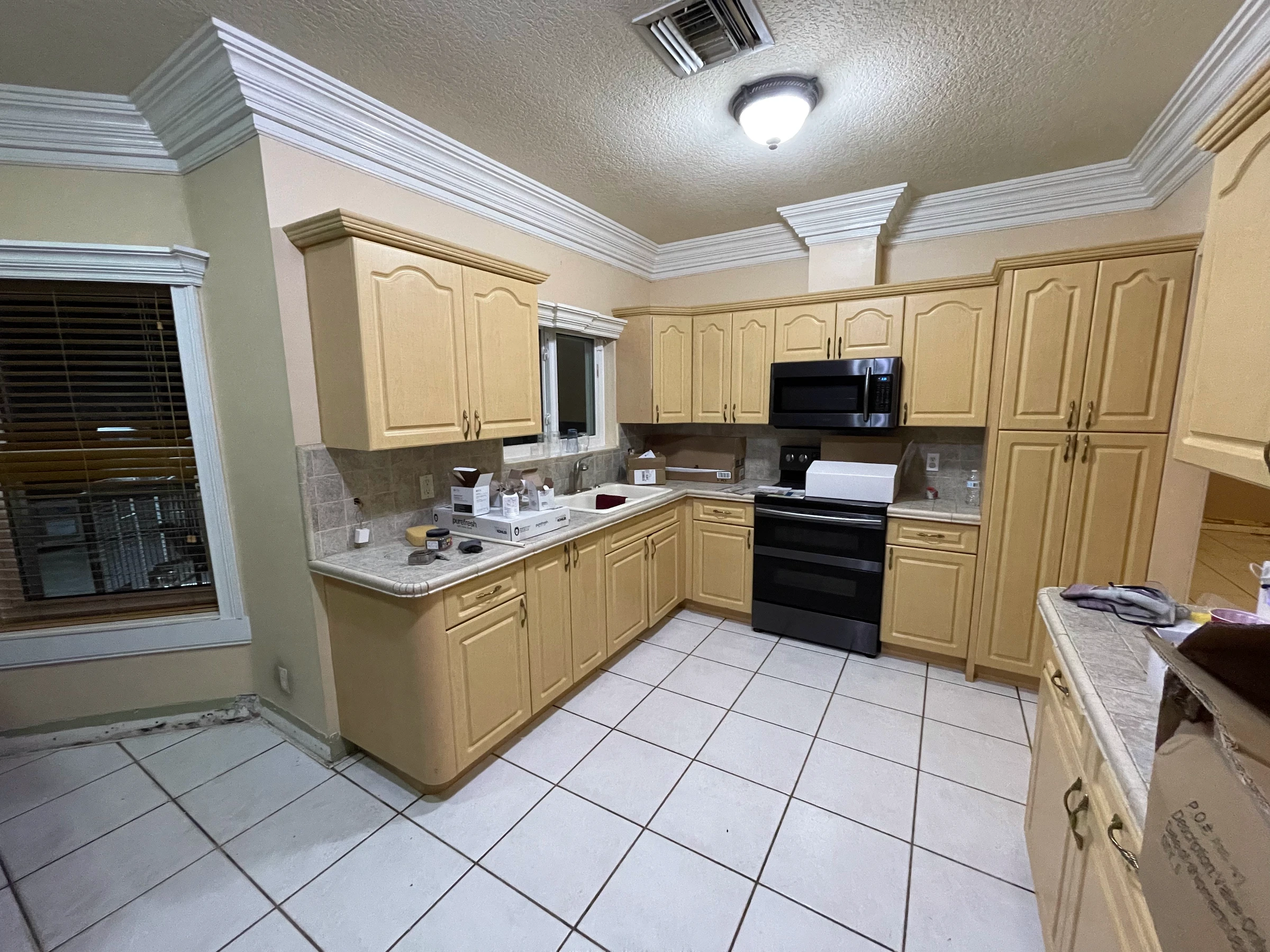 The same kitchen before the remodel, with light oak cabinets and white tile